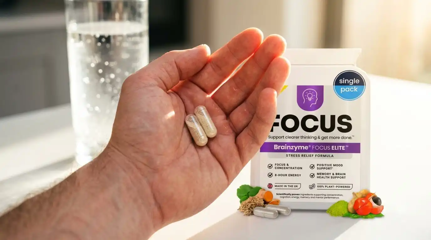 hand holding two Brainzyme Focus Elite capsules with water