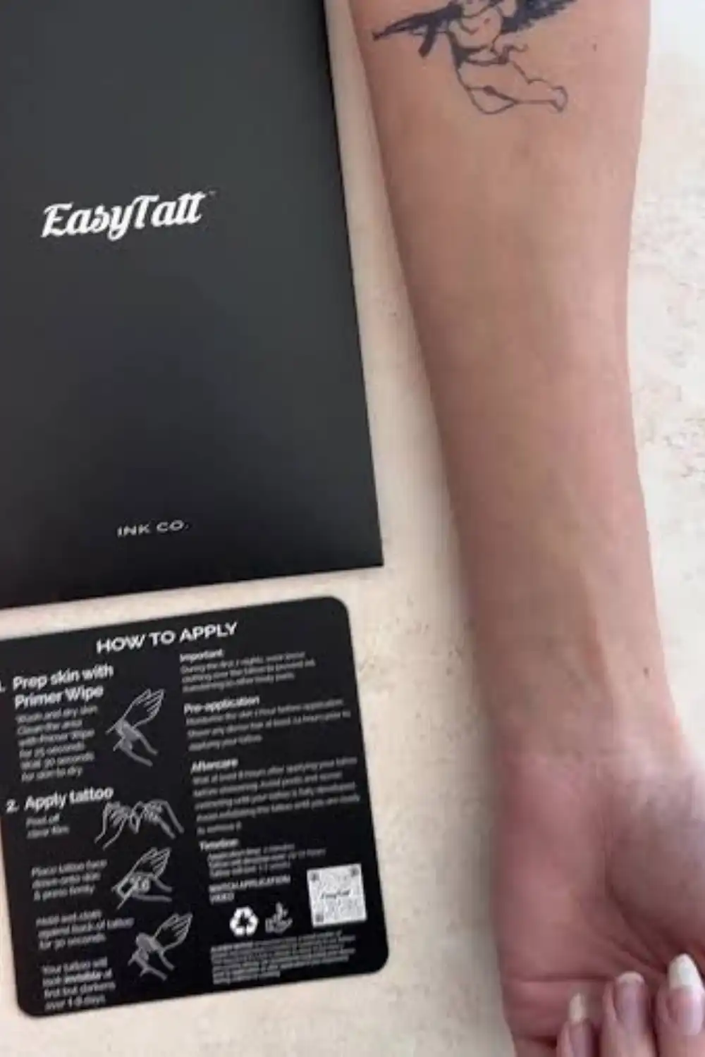 EasyTatt how to apply card and black packaging next to a forearm with a cherub tattoo