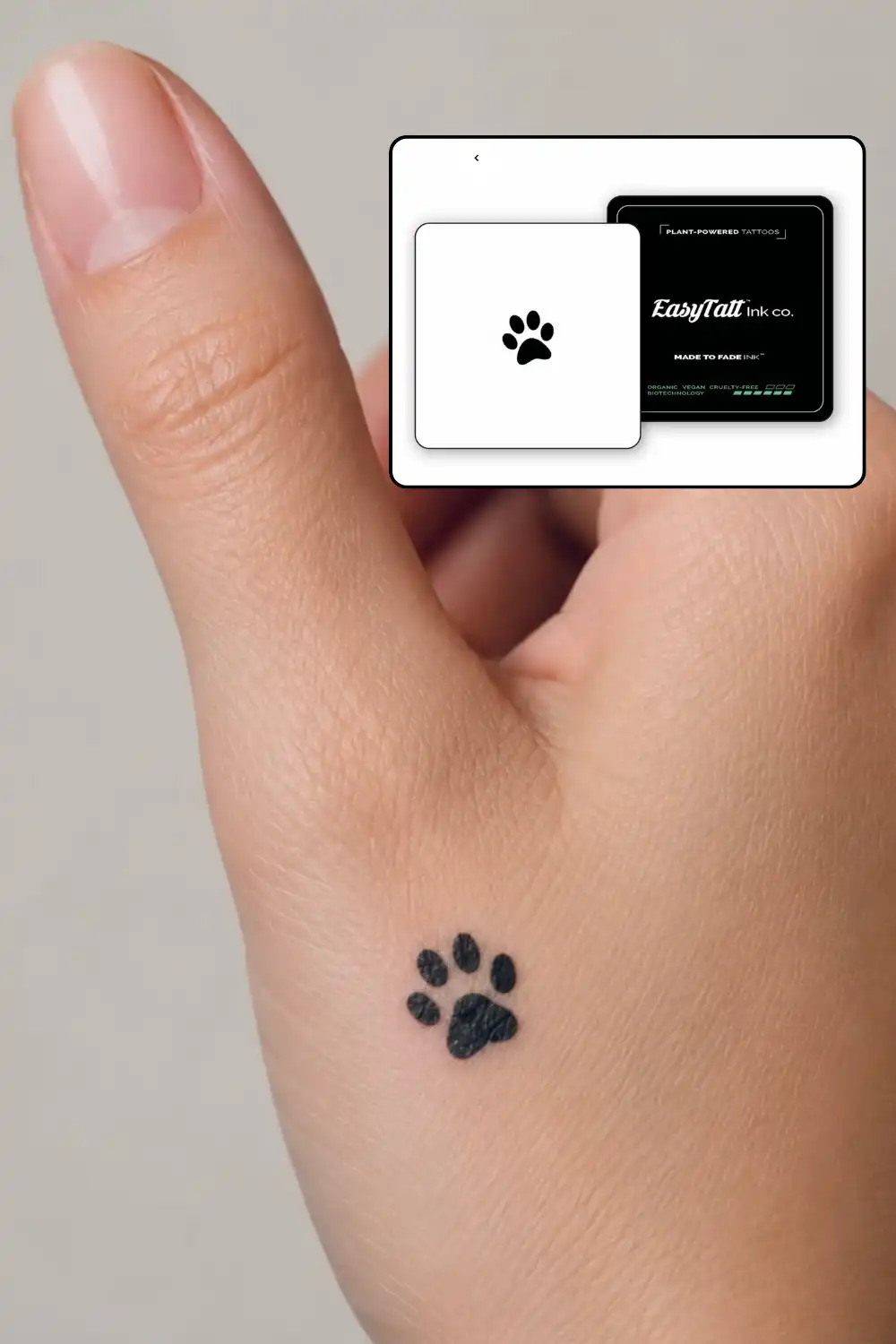 Small black paw print EasyTatt semi-permanent tattoo on the hand near the thumb, with the EasyTatt Ink co. pack