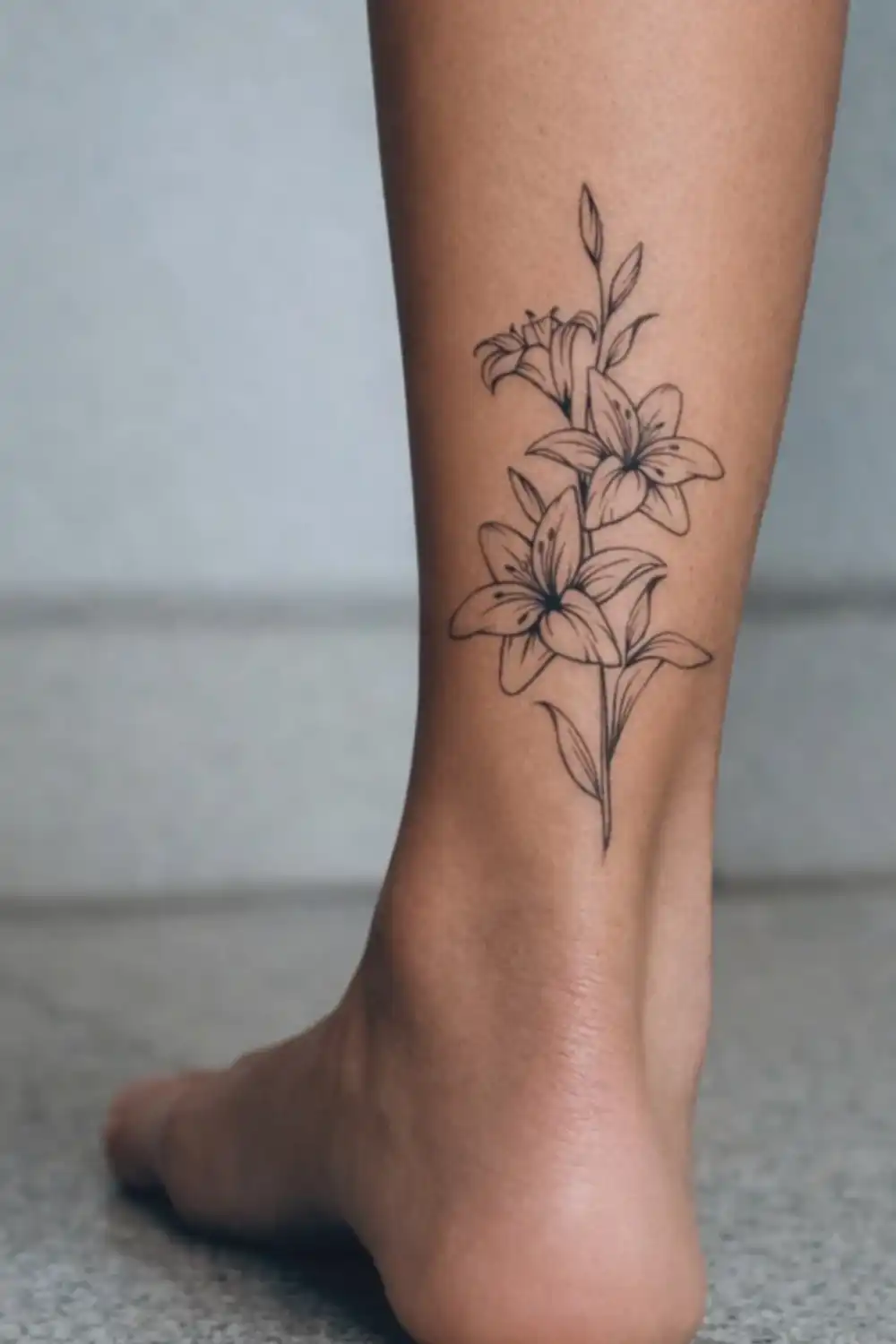 EasyTatt review photo of a fine-line lily flower temporary tattoo applied to the back of a lower leg above the ankle