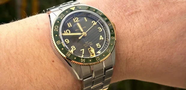 Wrist view of an Aethelsohn Horizon GMT watch with a green bezel and gold numerals during an Aethelsohn Horizon GMT review.