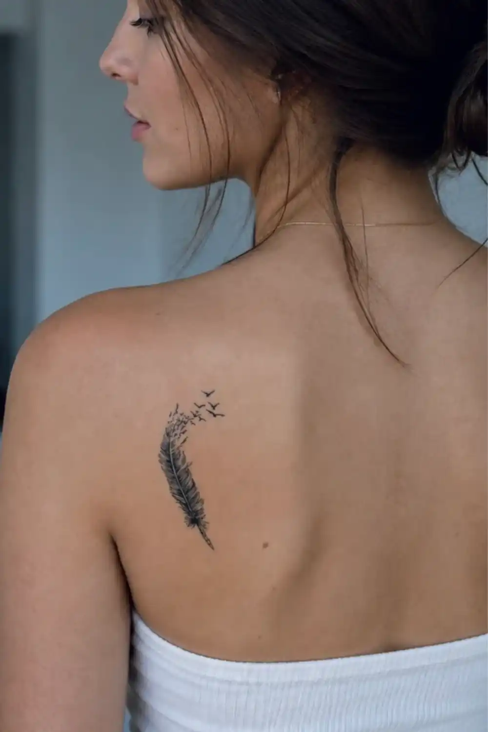 Woman's back with a feather tattoo turning into flying birds on her shoulder blade, EasyTatt semi permanent tattoo