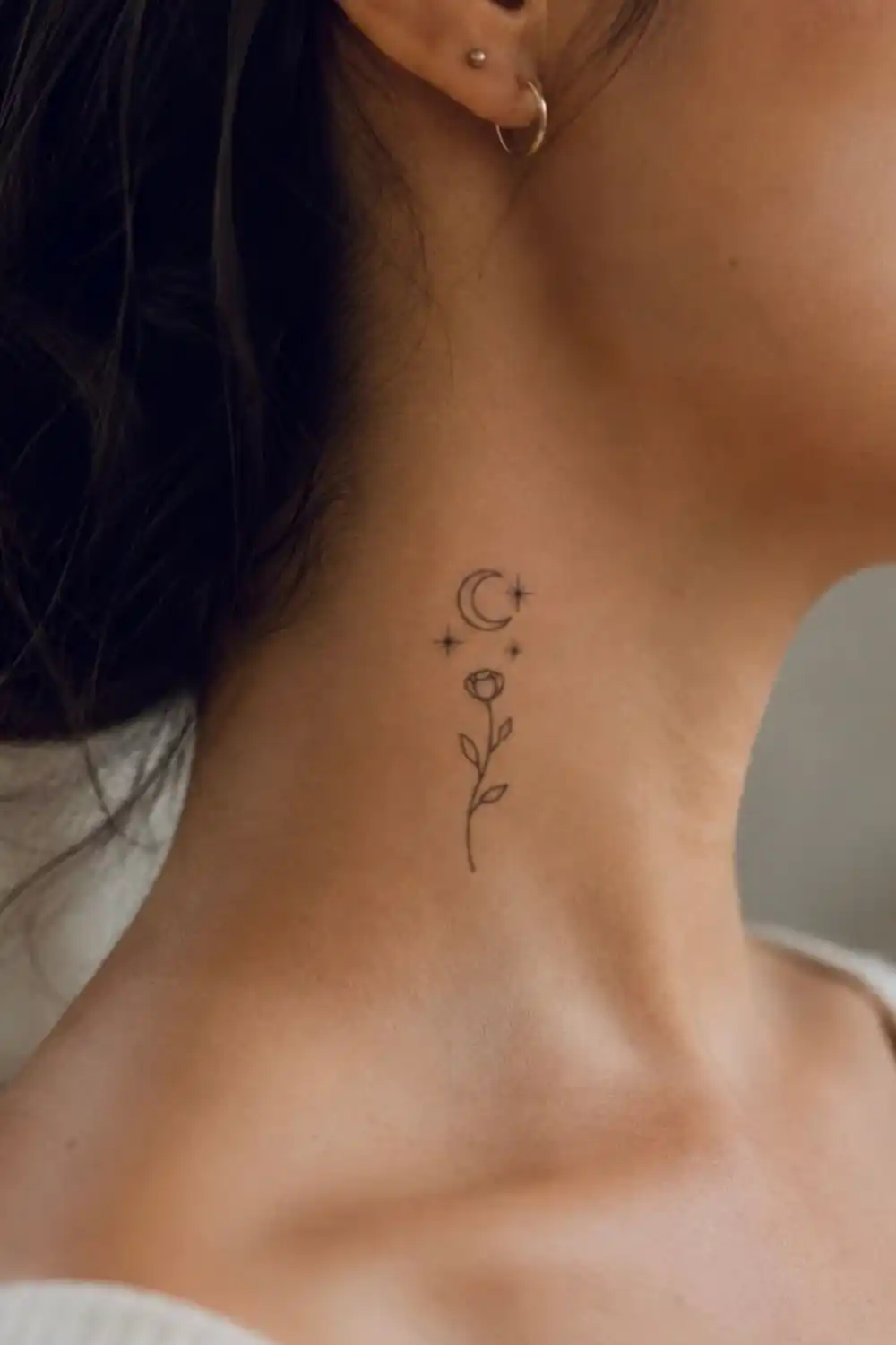 Fine-line moon, stars and rose temporary tattoo on the side of a woman's neck